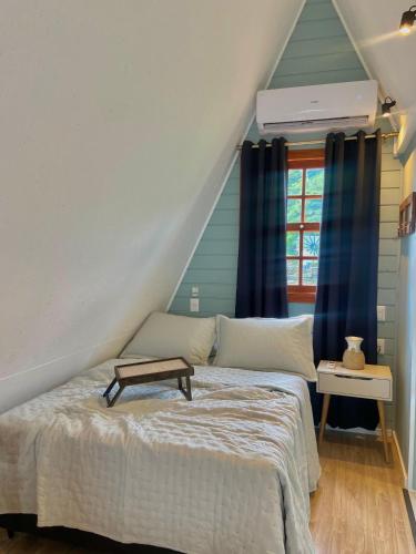 a bedroom with a bed with blue curtains at Chalé Pé do Morro in Penha