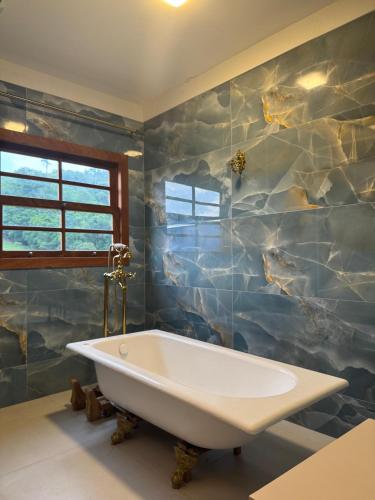 a bath tub in a bathroom with a stone wall at Chalé Pé do Morro in Penha