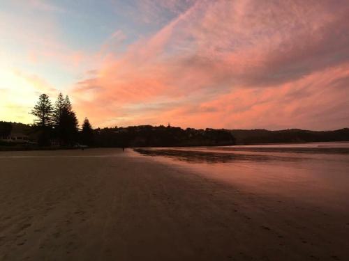 a view of a beach with a sunset at The Beach Pad in Auckland