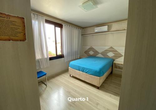 a bedroom with a blue bed and a window at Apartamento no Centro de Bento Gonçalves in Bento Gonçalves