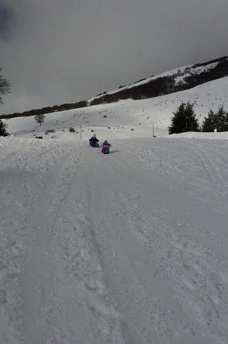 two people are riding down a snow covered slope at Passo del Mattino in Locati