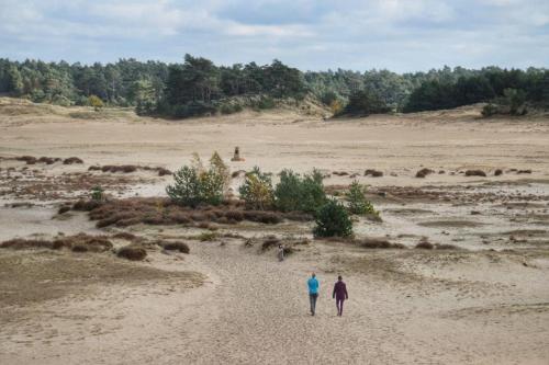 two people walking on a sandy field at Luxe Hottub Japandi Tiny house in het Bos in Nunspeet
