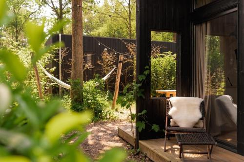 a chair sitting on the porch of a house at Luxe Hottub Japandi Tiny house in het Bos in Nunspeet