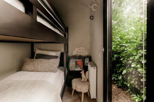 a small bedroom with a bunk bed and a plant at Luxe Hottub Japandi Tiny house in het Bos in Nunspeet