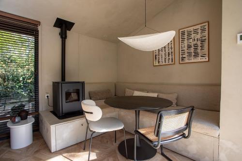 a living room with a table and chairs and a tv at Luxe Hottub Japandi Tiny house in het Bos in Nunspeet