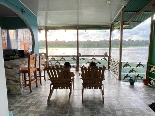 two people sitting in chairs looking out at the water at Casa Los Delfines in Tortuguero
