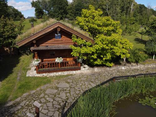 a log cabin with a grass roof and a pond at Srub RANCH NA HRANICI in Baška