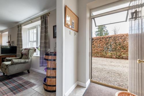 a living room with a sliding glass door and a chair at Falls Cottage in Glenlivet