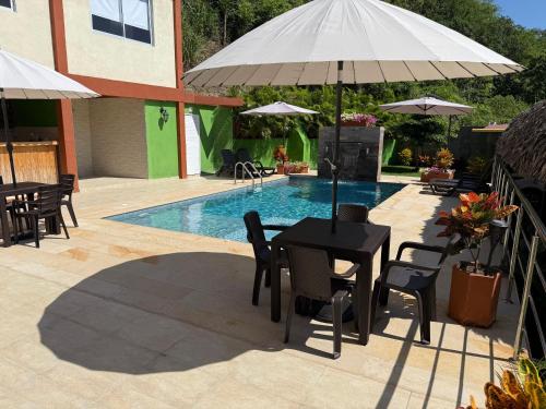 a table and chairs with an umbrella next to a pool at KETHALYA TAYRONA Hostal in El Zaino