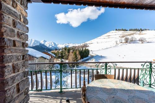 a balcony with a table and a view of snow covered mountains at Chalet les aiguilles in Albiez-Montrond
