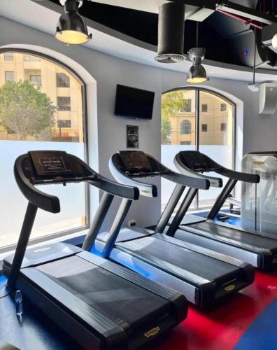 a row of treadmills in a gym with windows at Ahlan New Horizon JBR in Dubai