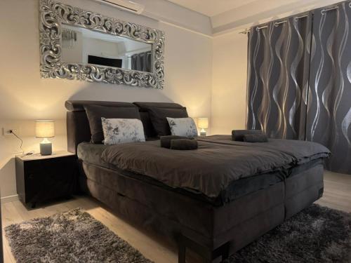 a bedroom with a large bed with a mirror on the wall at Lux Grey in Đakovo