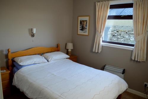 a bedroom with a white bed and a window at Bachylis Self Catering in Kirkwall