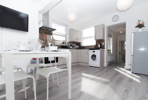 a white kitchen with a white table and chairs at SAV - 4 Bed Town House, Harrow in Harrow