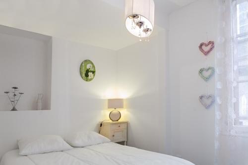 a white bedroom with a bed and a lamp at Appartement Avec Terrasse in Honfleur