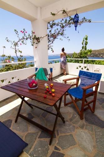 a wooden table and chairs on a balcony with a woman at Thalassia Studios in Kalamitsa