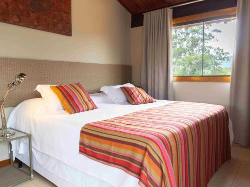 a bedroom with a white bed with a striped blanket at Casa da Lua Pousada in Alto Paraíso de Goiás