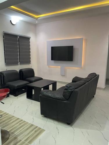 a living room with two black couches and a flat screen tv at Plot9 Road9 NTA road in Port Harcourt