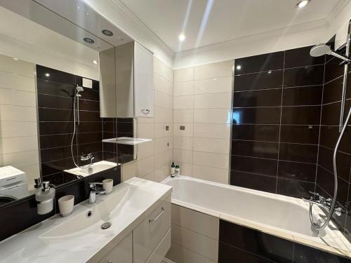 a bathroom with a tub and a sink and a mirror at High rise cozy 2BRD flat in Prague