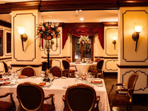 a dining room with tables and chairs and flowers at Plaza Grande Hotel in Quito