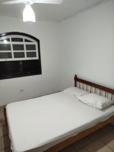 a white bed in a room with a window at Casa com piscina proximo da praia in Itapoa