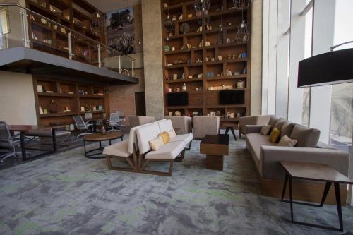 a lobby with couches and tables in a building at Fiesta Inn Suites Aeropuerto del Bajío in Silao