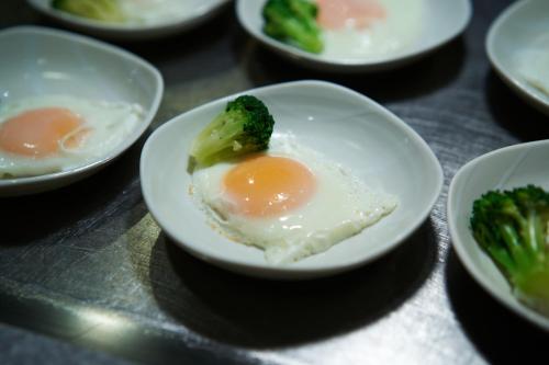 a plate with an egg and broccoli on a table at Dormy Inn Higashi Muroran in Muroran