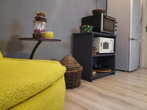 a living room with a yellow couch and a microwave at In House in Tbilisi City