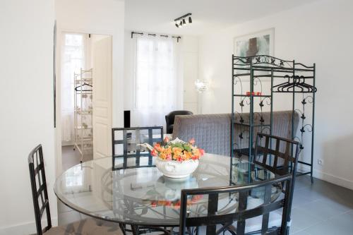 a glass dining room table with a bowl of flowers on it at Appartement Avec Terrasse in Honfleur