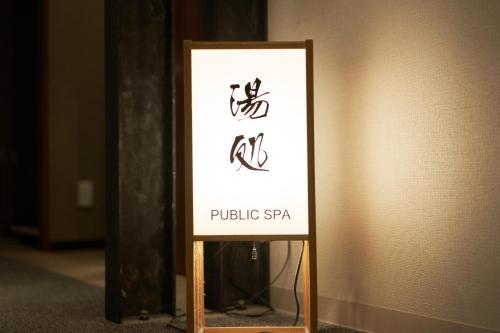 a sign for a public spa in a room at Dormy Inn Higashi Muroran in Muroran