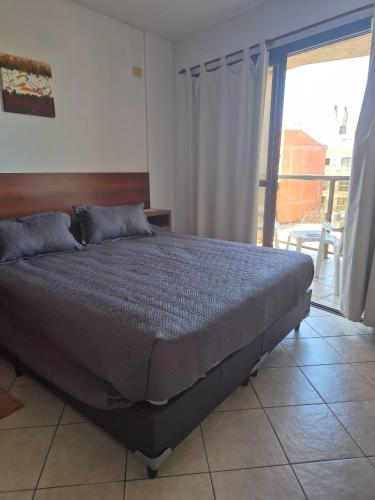 a large bed in a bedroom with a balcony at LUMINOSO Y COMPLETO DEPARTAMENTO CENTRO Villa Carlos Paz in Villa Carlos Paz