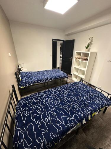 une chambre avec deux lits avec des draps bleus et blancs dans l'établissement Appartement rez de chaussée 4 personnes 2 chambres avec parking, à Coudekerque-Branche