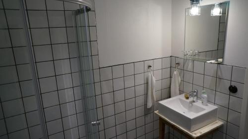 a white tiled bathroom with a sink and a mirror at Almbacka Logi in Skivarp