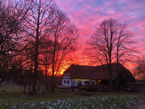 a sunset over a barn with trees and a building at Ferienwohnung Bergfeld in Bergfeld