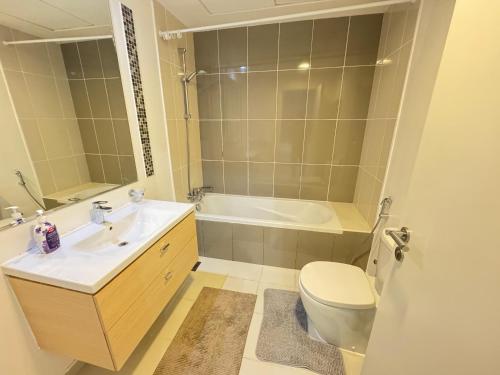 a bathroom with a sink and a toilet and a tub at Dubai damac hills luxurious appartment in Dubai