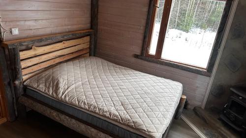 an empty bed in a room with a window at Upea hirsi mökki ulkoporeltaalla sekä kelosaunalla in Hämeenlinna