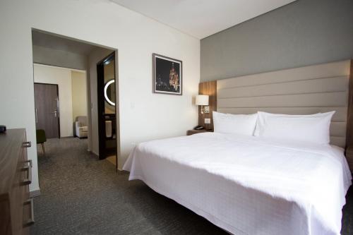 a large white bed in a hotel room at Fiesta Inn Suites Aeropuerto del Bajío in Silao