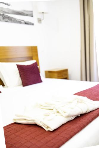 a bed with white sheets on top of it at Aldeia das Adegas in São Roque do Pico
