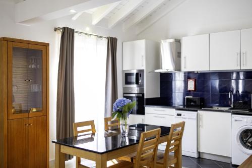 a kitchen with a dining table with chairs and a tableablish at Aldeia das Adegas in São Roque do Pico