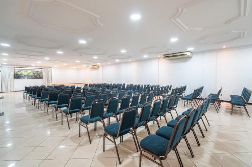 a room with rows of chairs and a white wall at Hotel Plaza Mayor in Santo André
