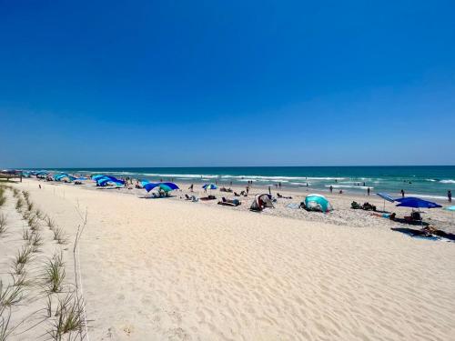 a group of people sitting on a beach with umbrellas at 104 Queen Pet Friendly Suite, 1st Floor Nest in Surf City