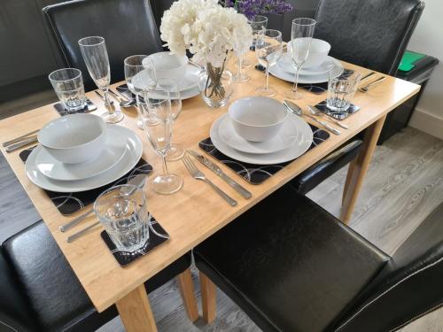 a wooden table with plates and glasses on it at SAV Nottingham Road 1 & 2 Bed Flats Loughborough in Loughborough