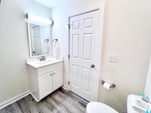 a white bathroom with a sink and a mirror at 104 Queen Pet Friendly Suite, 1st Floor Nest in Surf City