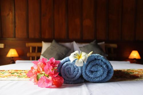a blue towel and flowers on a bed at Balakosa Gili Meno Bungalow in Gili Meno