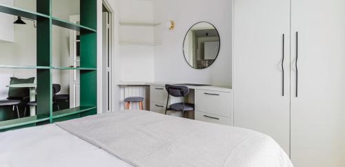 une chambre avec un lit blanc et un miroir dans l'établissement Appartement d'une chambre, à Paris