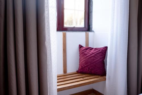 a purple pillow sitting on a wooden bench in a window at Aldeia das Adegas in São Roque do Pico