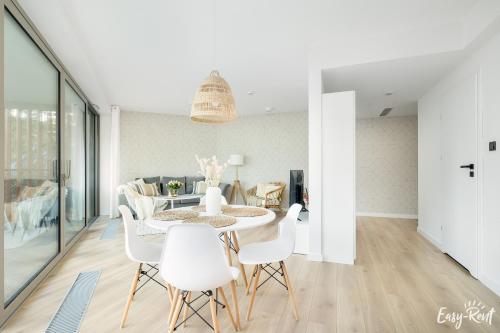 a dining room with a table and white chairs at Pinea 110 - basen, sauna, jacuzzi w cenie pobytu - bezpośredni widok na morze - Easy - Rent Apartments in Pobierowo
