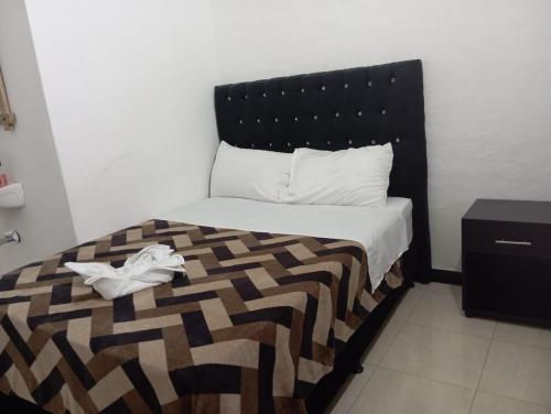 a bed with a black headboard and a pair of shoes at Hotel Casa Corleone in Garzón