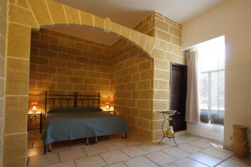 アルベロベッロにあるレジデンツァ デ レオナルディス のレンガの壁にベッド1台が備わるベッドルーム1室