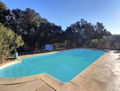 une grande piscine bleue avec des arbres en arrière-plan dans l'établissement La bonne adresse de Provence, à Cornillon-Confoux